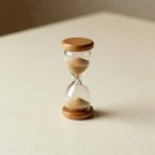 A small hourglass alone on a cream surface